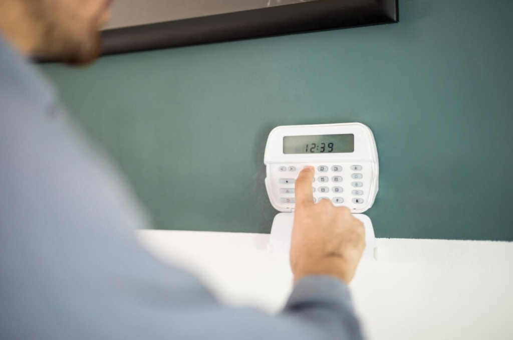 A man pressing a button on a digital wall clock with a keypad interface